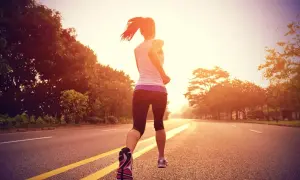 Mujer corriendo por una carretera al atardecer, entrenando para la distancia media maratón.