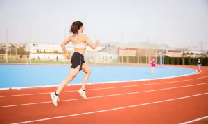 Mujer corriendo en pista de atletismo, lista para las noticias running.