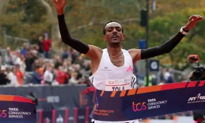 Tamirat Tola cruza la meta de la Maratón de Nueva York, victorioso, con los brazos en alto.