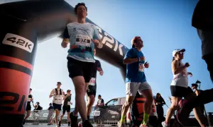 Corredores cruzan la meta de la media maratón bajo un arco inflable. El dorsal 974 destaca en un participante.