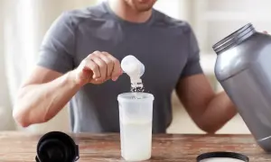 Hombre preparando su batido de proteina con agua o leche. Añade el polvo a un vaso mezclador.