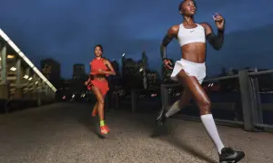 Dos corredoras entrenan al anochecer en la ciudad, aprendiendo como respirar al correr para mejorar su rendimiento.