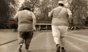 Dos personas con sobrepeso corren en una pista, un paso a la vez para adelgazar.