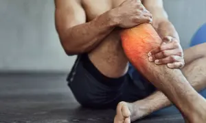 Hombre con dolor en la pantorrilla, con zona roja resaltada. A veces, es bueno hacer ejercicio con agujetas para fortalecer.
