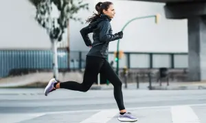 Mujer corriendo en la calle, demostrando una excelente técnica de carrera.