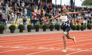 Sifan Hassan cruza la meta en un maratón, con los brazos extendidos y una expresión de júbilo.