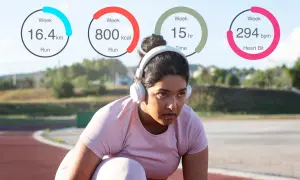 Mujer con auriculares en una pista de atletismo, con estadísticas de ejercicio: 16.4 km, 800 kcal, 15 horas y 294 bpm. ¡Controla tus calorías diarias!