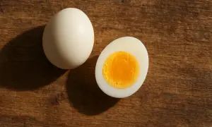 Un huevo cocido entero y otro partido por la mitad, mostrando su yema dorada. Un alimento rico en proteínas para empezar el día.