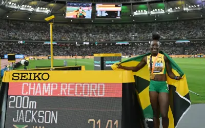 Shericka Jackson, campeona y récord en 200m, celebra con la bandera de Jamaica y su medalla de oro.