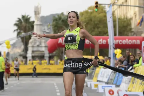 Meritxell Soler cruza la meta de una carrera en Barcelona, con el dorsal 51 y una expresión de esfuerzo.