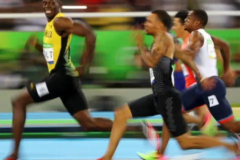 Usain Bolt, con su icónico uniforme amarillo, lidera la carrera de 100m, buscando batir su propio récord.
