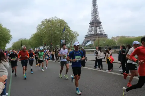 Corredores participan en el maratón de París, con la Torre Eiffel como telón de fondo.