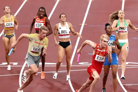 Atletas compiten en una carrera de relevos 4x400 mixto. El equipo de Alemania lidera, con España y Bélgica cerca.