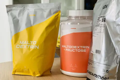 Bolsas y bote de suplementos deportivos con "Maltodextrin" y "Maltodextrin + Fructose". Aunque la maltodextrina es mala para algunos, aquí se presenta como opción.