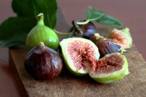 Frescos higos verdes y morados, algunos cortados, listos para comer.