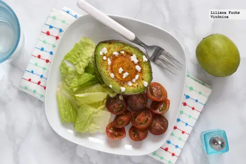 Aguacate horneado con queso y especias, acompañado de lechuga y tomates cherry. Un ejemplo de deliciosos alimentos cetogenicos.