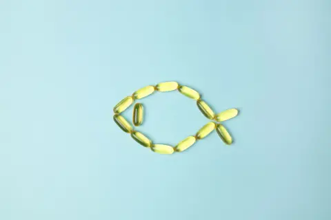 Cápsulas de aceite de pescado forman un pez, representando los omega 3 beneficios y contraindicaciones.
