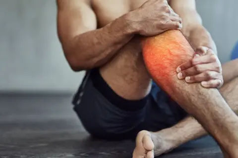 Hombre con dolor en la pantorrilla, con zona roja resaltada. A veces, es bueno hacer ejercicio con agujetas para fortalecer.