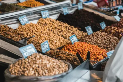 Montones de frutos secos en un mercado, incluyendo almendras que engordan.