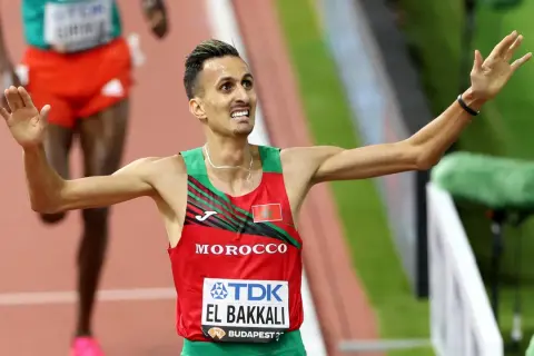 Soufiane El Bakkali, atleta marroquí, celebra su victoria en la pista, con los brazos en alto y una expresión de júbilo.