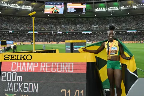 Shericka Jackson, campeona y récord en 200m, celebra con la bandera de Jamaica y su medalla de oro.