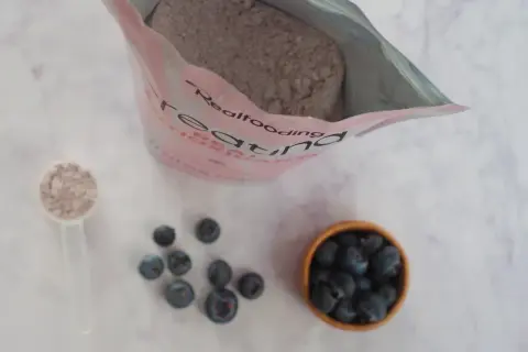 Bolsa de creatina, cucharada de polvo y arándanos. Consulta sobre creatina y embarazo.