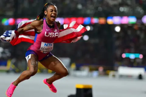 Sha'Carri Richardson, campeona 100 metros femeninos atletismo, celebra con la bandera de EE. UU. tras ganar.