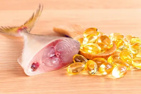 Un trozo de pescado fresco junto a cápsulas doradas, representando los **aceite de hígado de bacalao beneficios** para la salud.