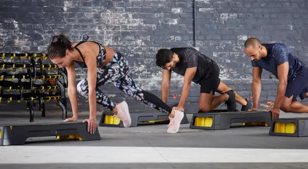 Tres personas hacen ejercicio en step. Queman que son las calorías con cada movimiento.