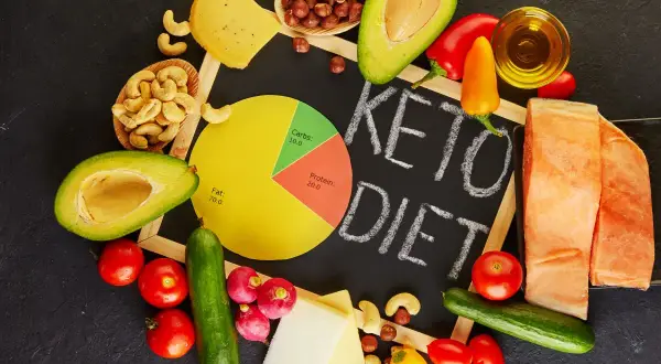 Ingredientes para una dieta keto: aguacate, salmón, queso, frutos secos, verduras y aceite.