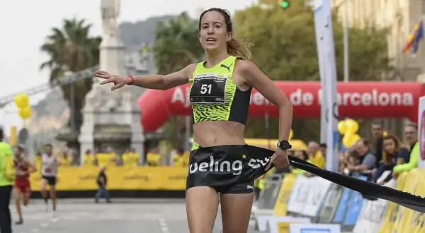 Meritxell Soler cruza la meta de una carrera en Barcelona, con el dorsal 51 y una expresión de esfuerzo.