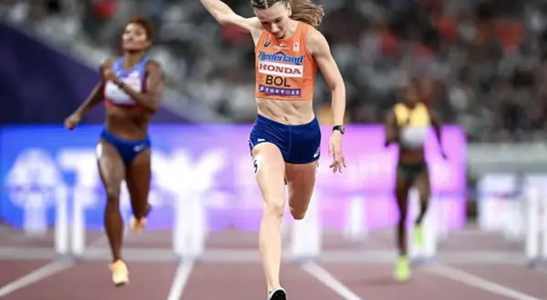 Femke Bol cruza la meta en una carrera de atletismo, con otras competidoras detrás.