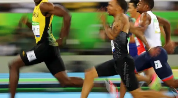 Usain Bolt, con su icónico uniforme amarillo, lidera la carrera de 100m, buscando batir su propio récord.