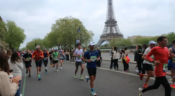 Corredores participan en el maratón de París, con la Torre Eiffel como telón de fondo.