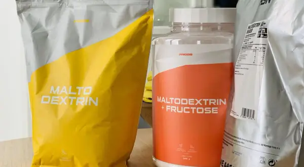 Bolsas y bote de suplementos deportivos con "Maltodextrin" y "Maltodextrin + Fructose". Aunque la maltodextrina es mala para algunos, aquí se presenta como opción.