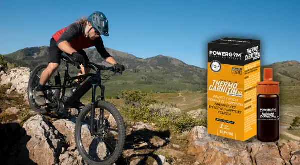 Ciclista de montaña desciende por terreno rocoso. A su lado, caja y vial de Powergym Thermo Carnitina XL, para saber como tomar l carnitina.