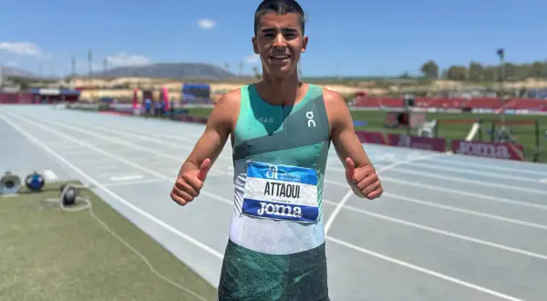 Mohamed Attaoui, atleta sonriente con dorsal, da pulgares arriba en la pista de atletismo.
