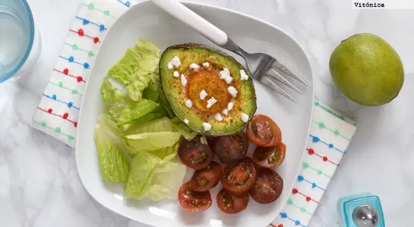 Aguacate horneado con queso y especias, acompañado de lechuga y tomates cherry. Un ejemplo de deliciosos alimentos cetogenicos.
