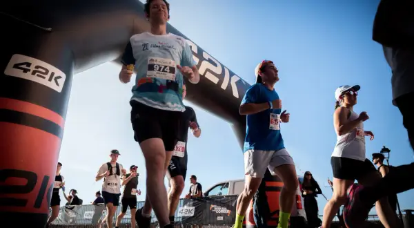 Corredores cruzan la meta de la media maratón bajo un arco inflable. El dorsal 974 destaca en un participante.