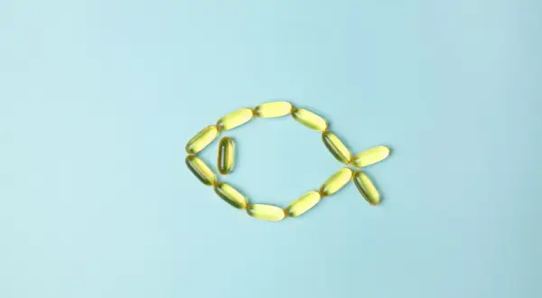 Cápsulas de aceite de pescado forman un pez, representando los omega 3 beneficios y contraindicaciones.