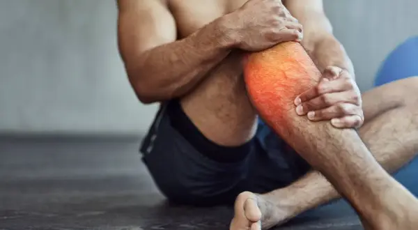 Hombre con dolor en la pantorrilla, con zona roja resaltada. A veces, es bueno hacer ejercicio con agujetas para fortalecer.