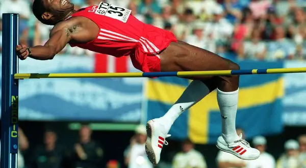Atleta en pleno salto de altura, superando la barra en un intento por batir el récord mundo salto altura.