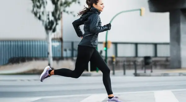Mujer corriendo en la calle, demostrando una excelente técnica de carrera.
