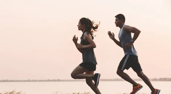 Pareja corriendo al amanecer. Para mantener la energía, es importante saber como tomar electrolitos.