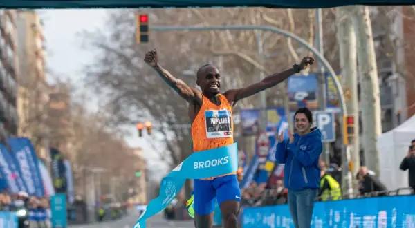 Atleta cruza la meta, celebrando su victoria y un posible récord de 1500 metros. El cronómetro marca 00:56:42.