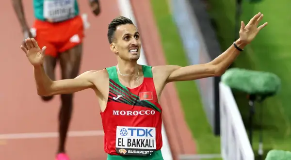 Soufiane El Bakkali, atleta marroquí, celebra su victoria en la pista, con los brazos en alto y una expresión de júbilo.