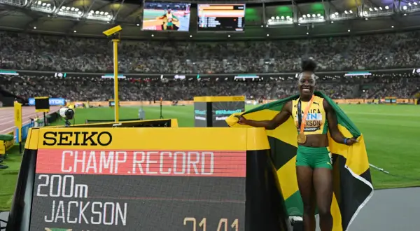 Shericka Jackson, campeona y récord en 200m, celebra con la bandera de Jamaica y su medalla de oro.
