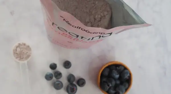 Bolsa de creatina, cucharada de polvo y arándanos. Consulta sobre creatina y embarazo.