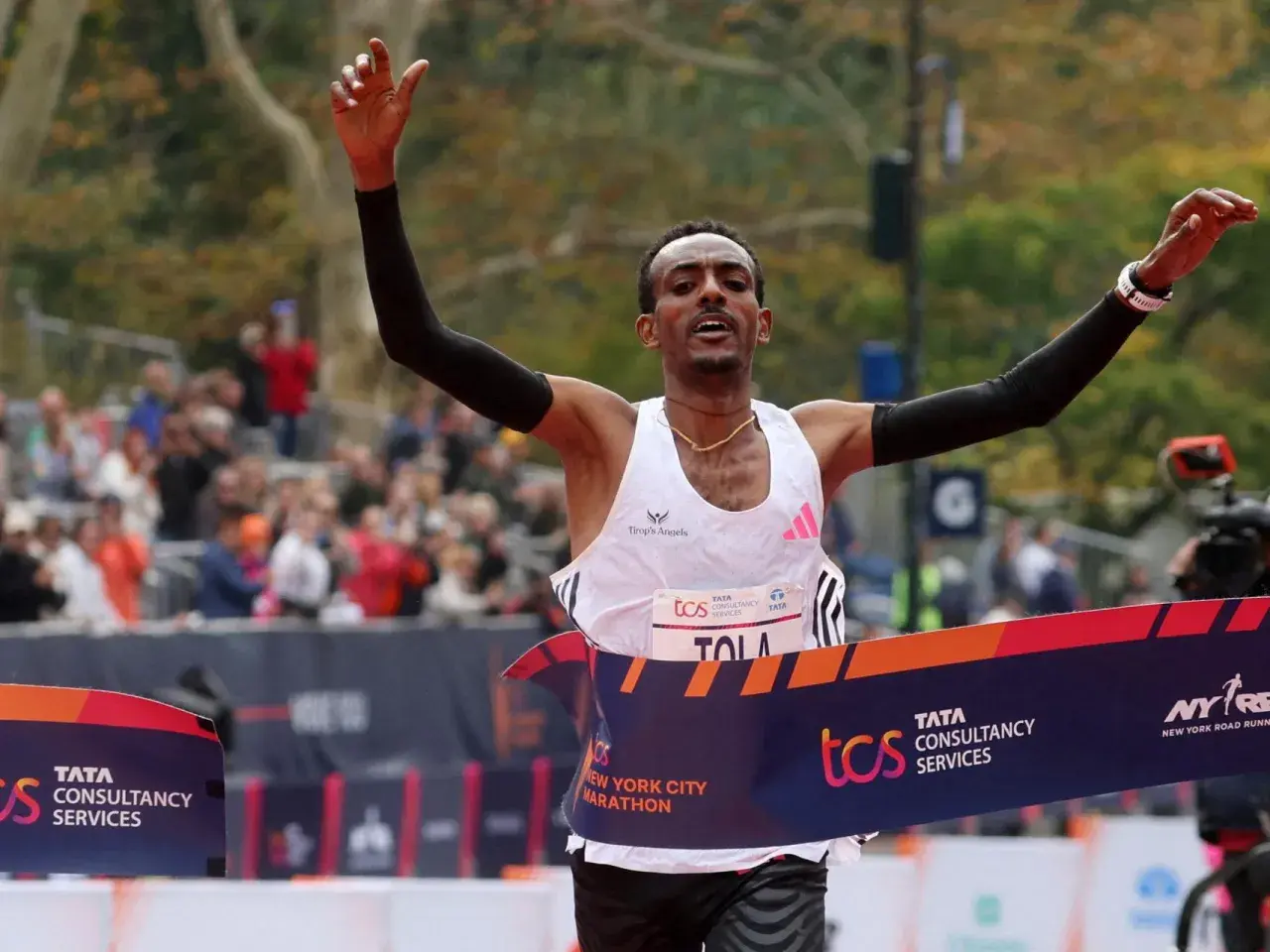 Tamirat Tola cruza la meta de la Maratón de Nueva York, victorioso, con los brazos en alto.