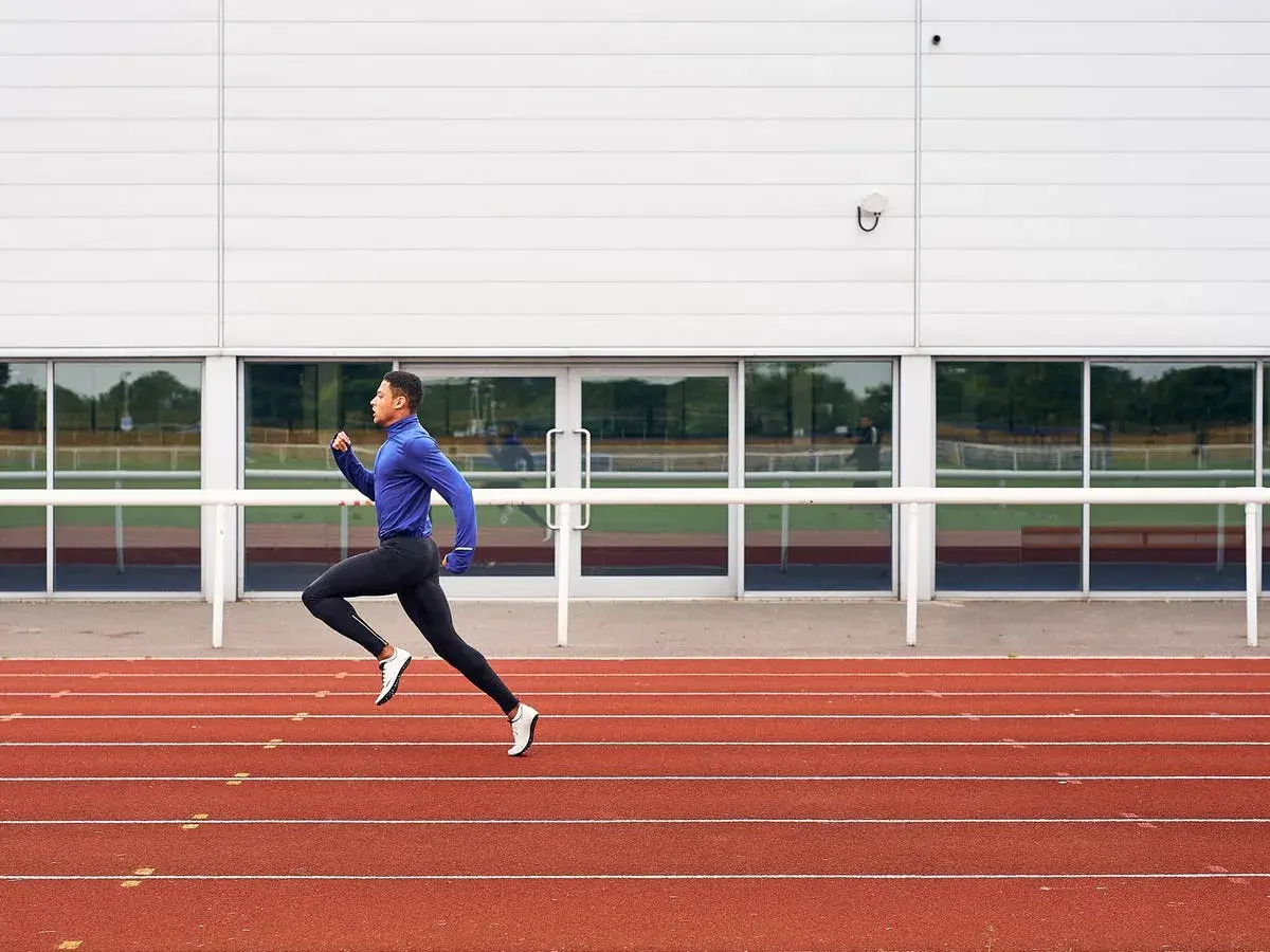 Atleta entrenando en pista de atletismo, preparándose para los 1500 metros.